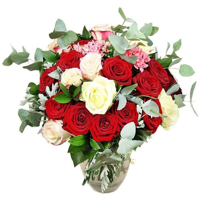 The photograph captures a luxurious rose arrangement set against a clean white background, the kind of scene you might expect from a professional studio or a meticulous florist in White City. The bouquet is lush and full, comprising more than two dozen roses arranged into a rounded, almost cloud-like dome that nearly spills over the rim of its clear glass vase. Deep crimson and bright scarlet roses form the passionate core, their velvety petals in varying stages of unfurling, from tight, promising buds to broad, fully open blossoms that reveal every layered whorl. Punctuating this intensity are creamy white and soft ivory roses, and a few white flowers whose edges are delicately tinged with the lightest blush pink, bringing gentle light and harmony to the decisive reds. Throughout the design, small tufts of bright pink filler flowers, akin to mini carnations or other petite blooms, appear in the gaps between the larger roses, adding a touch of movement and intricate, almost lace-like texture. Surrounding and weaving between the flowers are elegant stems of blue-green eucalyptus, the round, slightly matte leaves cascading outward and giving the bouquet a contemporary, airy frame while suggesting a cool, invigorating scent. Supporting foliage in deeper greens and hints of silvery-green provides additional depth and makes the bouquet feel generously filled without losing its shape. The vase itself has a subtly bulbous base tapering into a narrower neck, allowing the viewer to see the neatly trimmed stems gathered in clear water, which reinforces the impression of freshly picked, well-cared-for blooms. Set against the stark background, this rose arrangement conveys an air of classic romance and celebration, ideal for marking an anniversary, a grand gesture of love, or a special delivery to a home near Westfield London or one of the modern developments around White City.